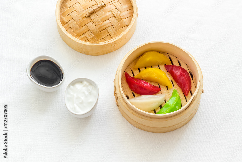 Colored dumplings in wooden steamer, top view