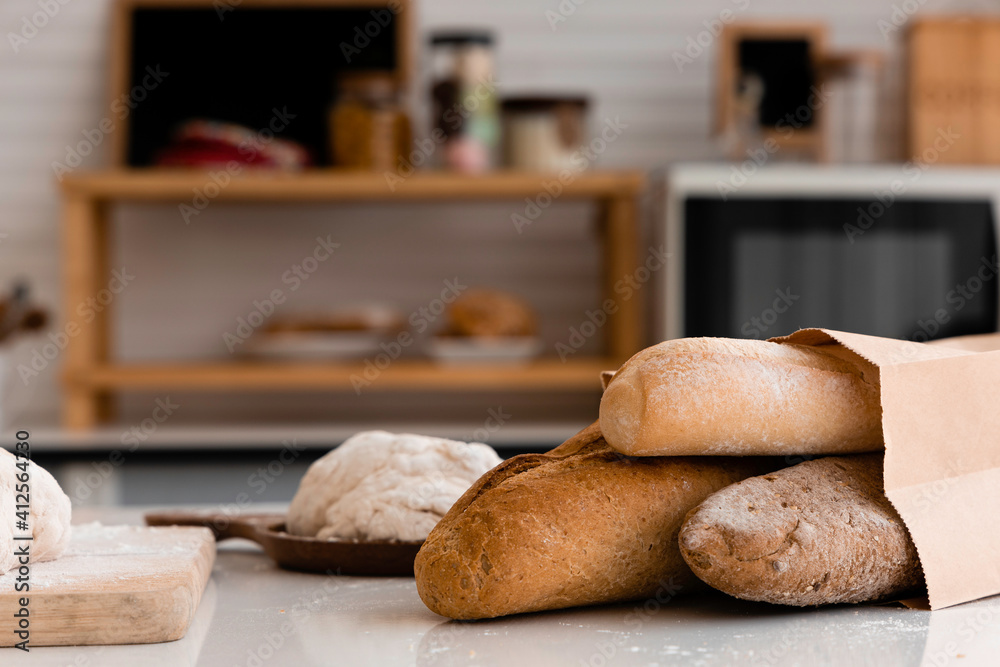 loaf of bread in paper bags and fresh dough on a table in the kitchen