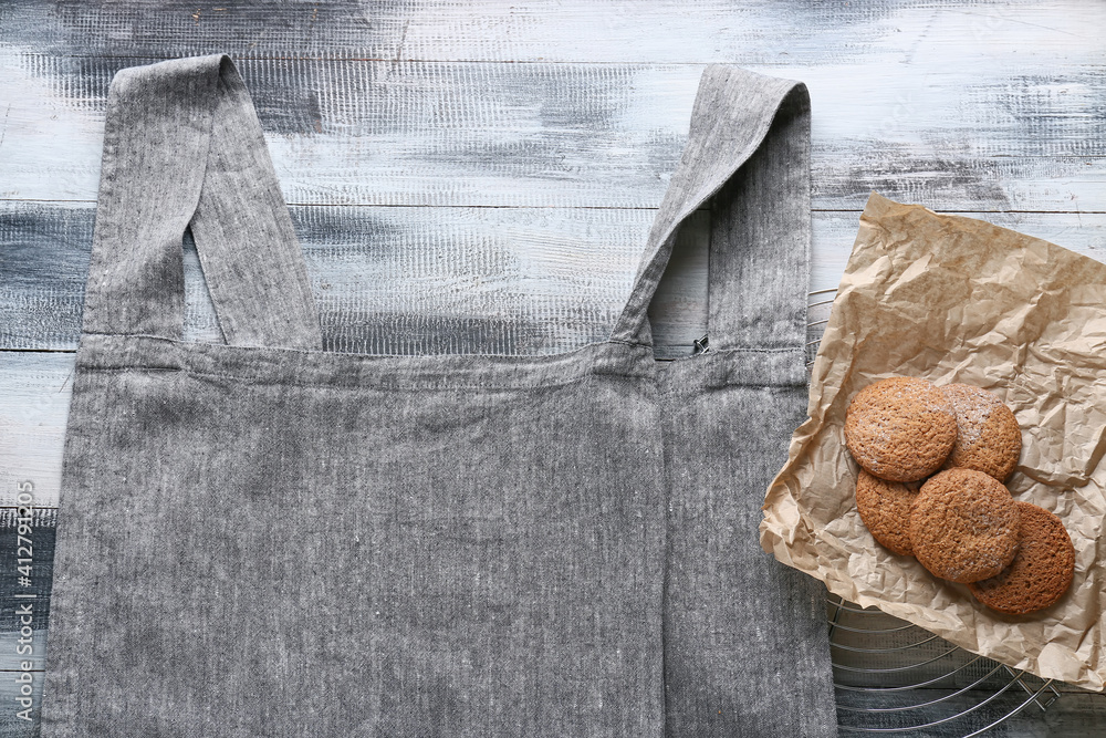 Clean apron and tasty cookies on wooden background