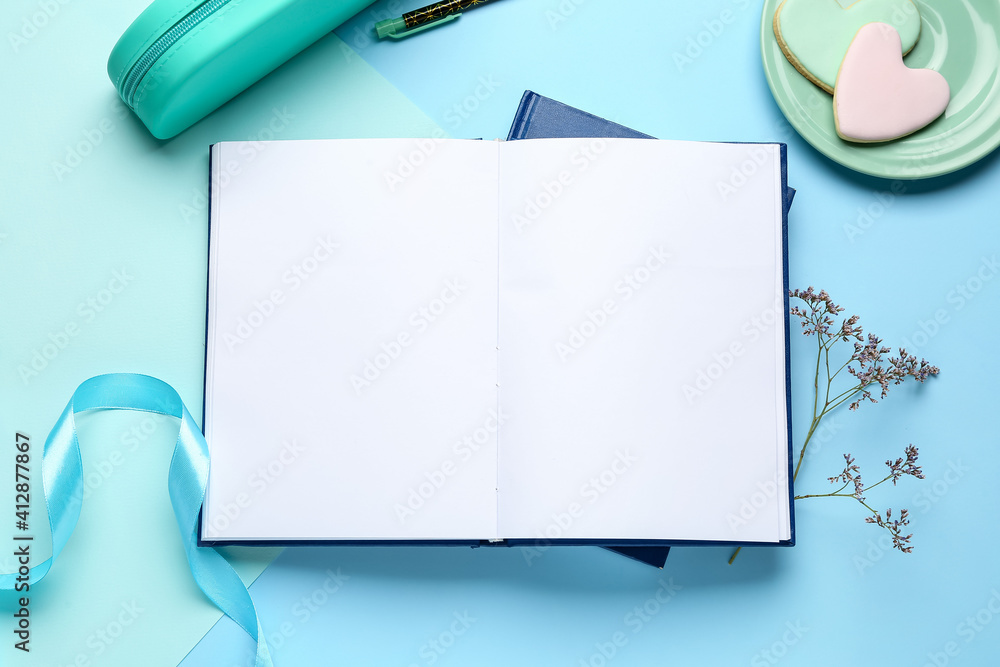 Blank book, cookies and ribbon on color background