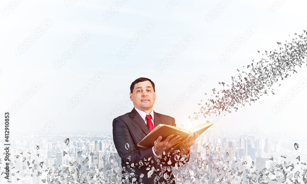 Serious businessman with open book looking up