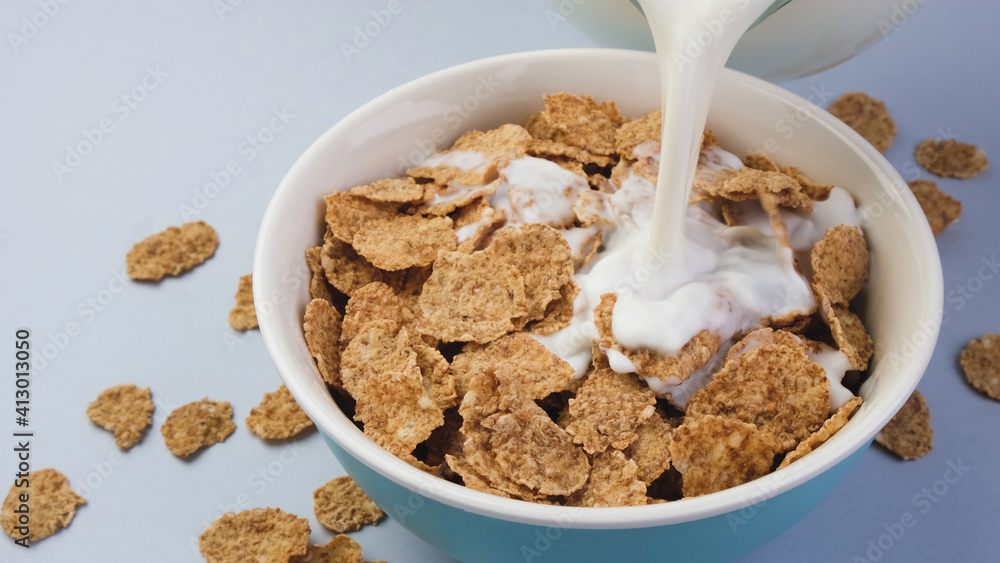 Milk pouring into bowl with bran flakes