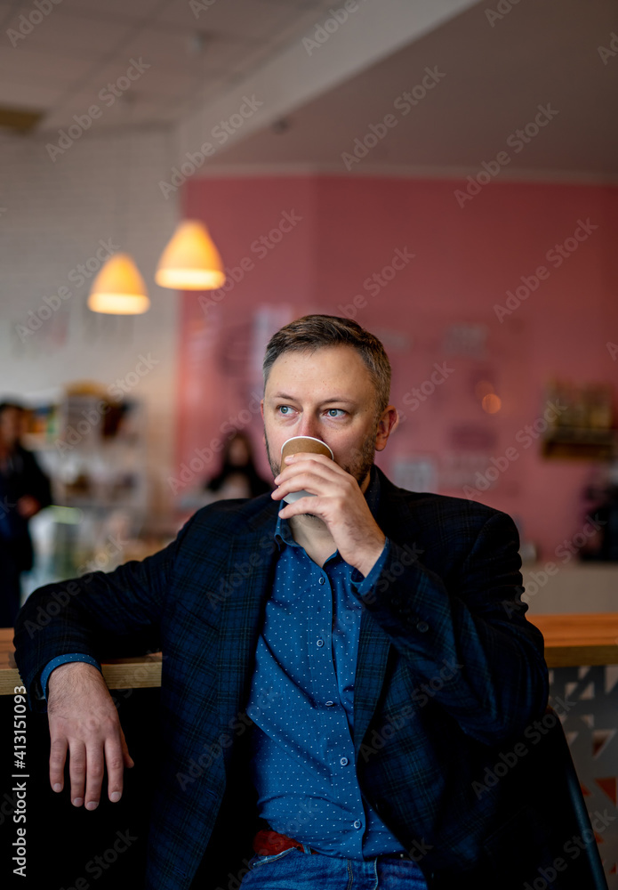 Thoughtful handsome guy relaxes in a cafe with a cup of hot drink. Modern cubby place.