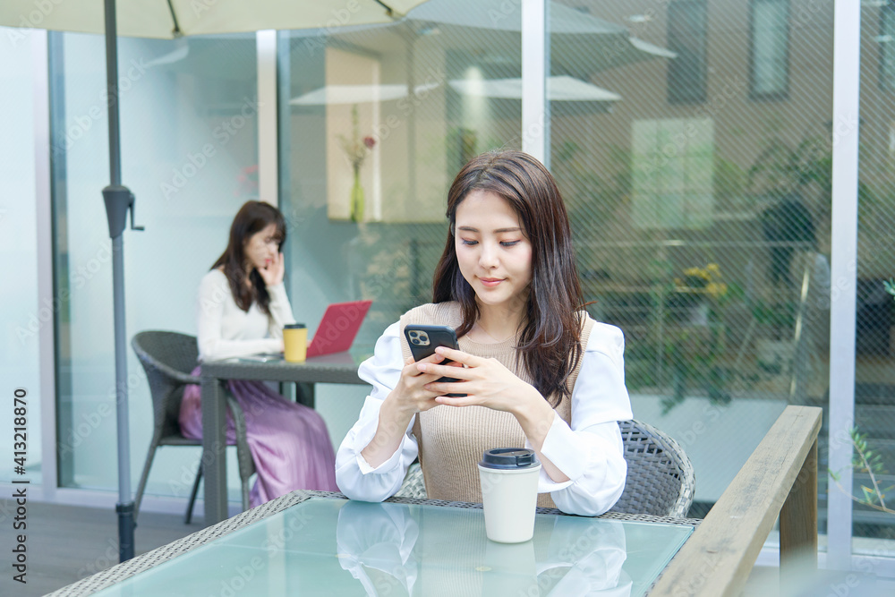 カフェテラスでスマホを使う女性