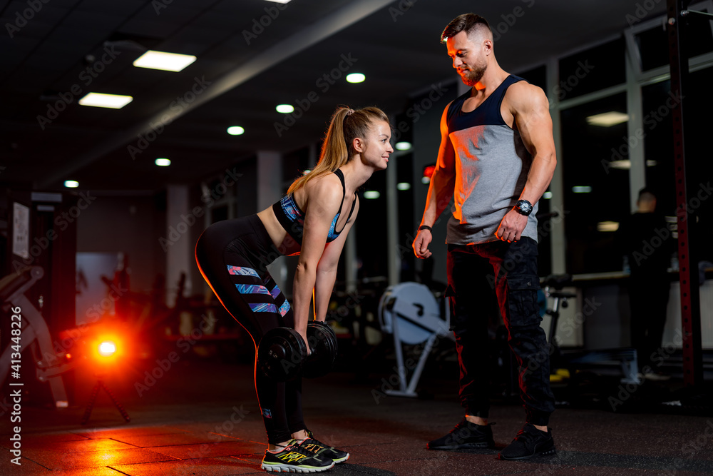 Strong young woman with beautiful athletic body doing exercises with personal trainer. Fitness, body