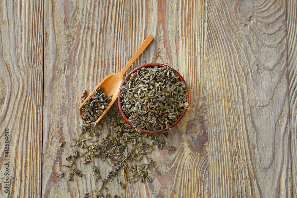 Bowl with dry tea leaves on wooden background