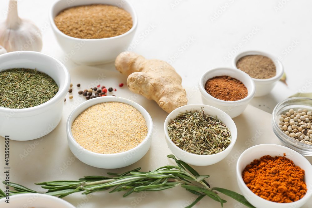 Bowls with different spices on light background