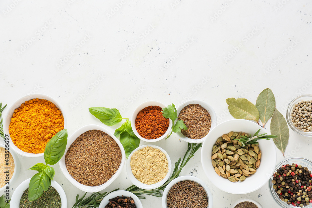 Bowls with different spices on light background