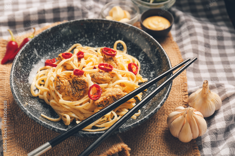 餐桌上有美味的面条、鸡肉和筷子的盘子