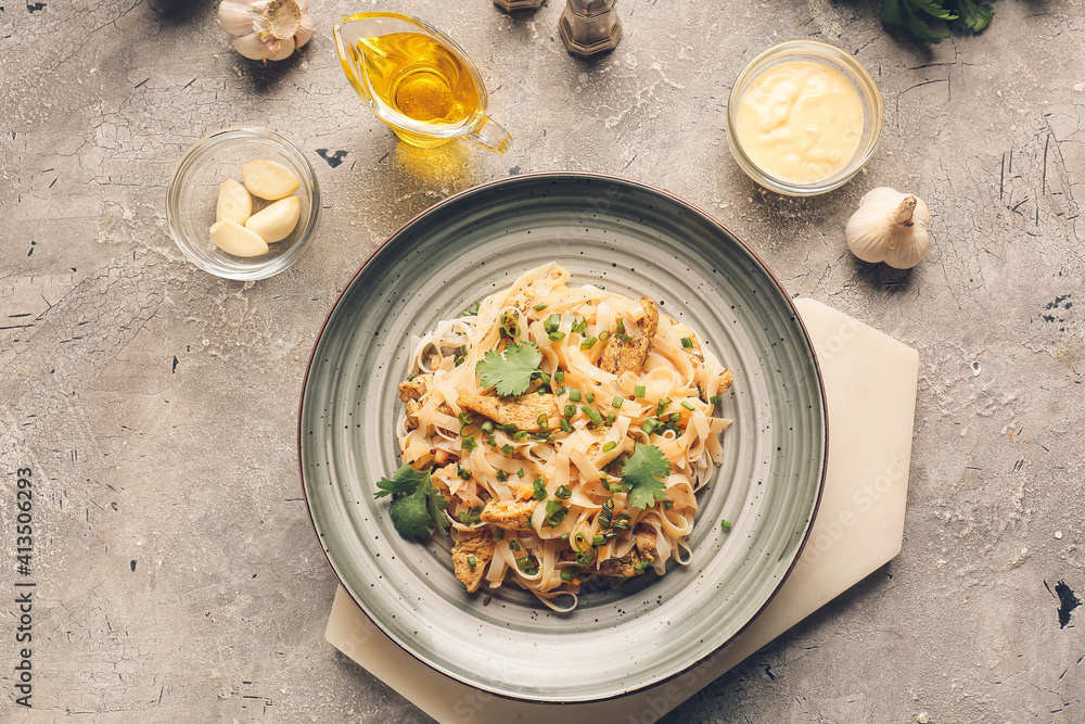 Plate with tasty noodles and chicken on dark background