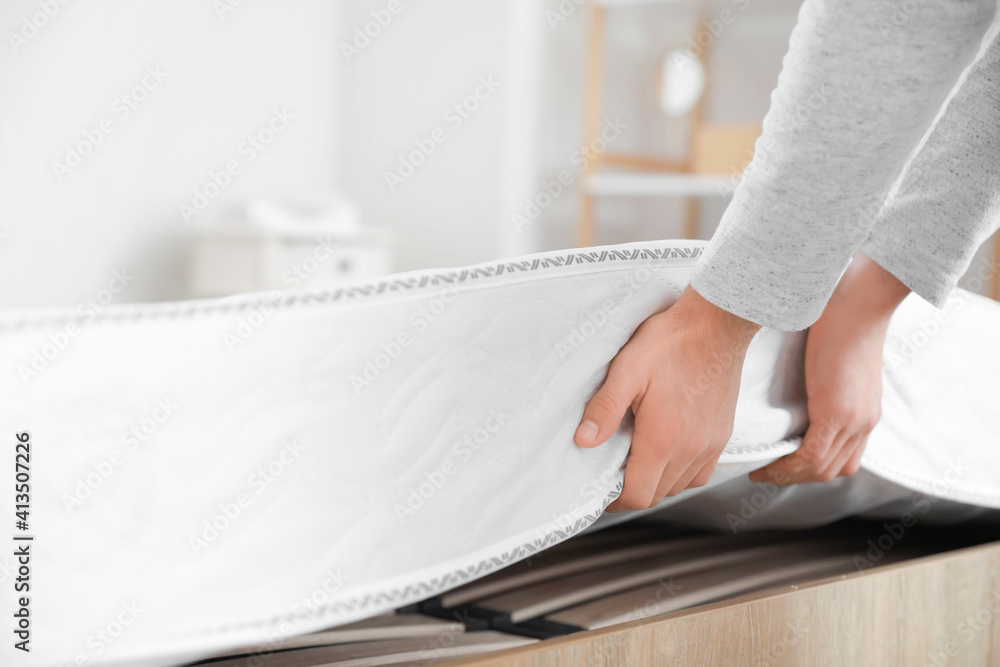 Man putting soft orthopedic mattress on bed