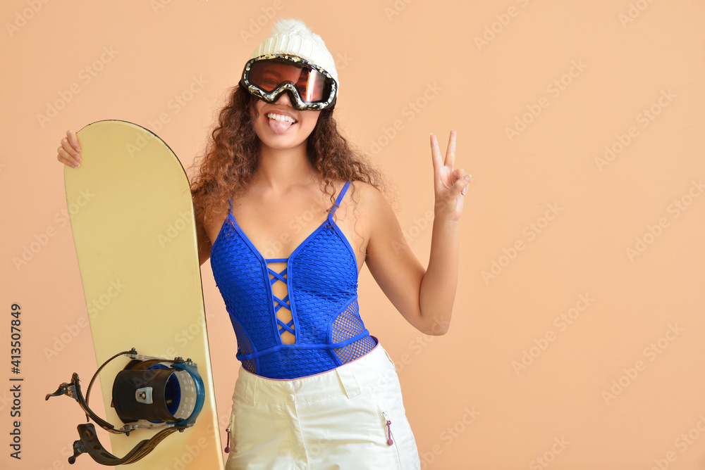 Female snowboarder showing victory gesture on color background