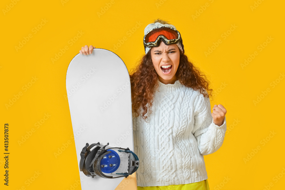 Aggressive female snowboarder on color background