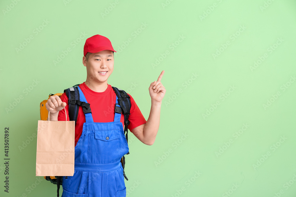 Courier of food delivery service pointing at something on color background