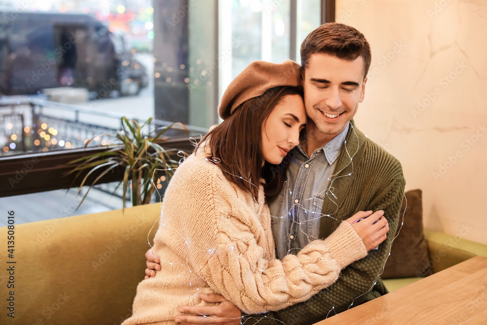 Happy young couple sitting in cafe on Christmas eve