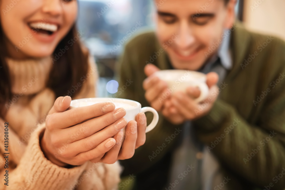 Happy young couple drinking hot chocolate in cafe on Christmas eve