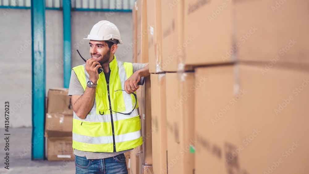 Professional cargo worker talks on portable radio to contact another worker . Factory and warehouse 