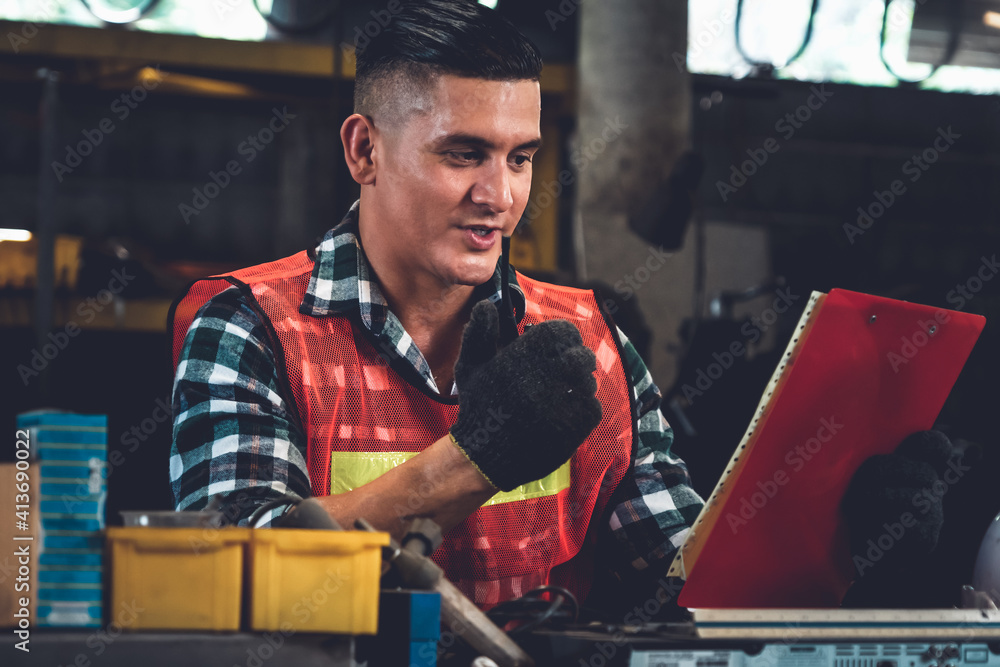 Factory worker talking on portable radio while inspecting machinery parts . Industrial and engineeri