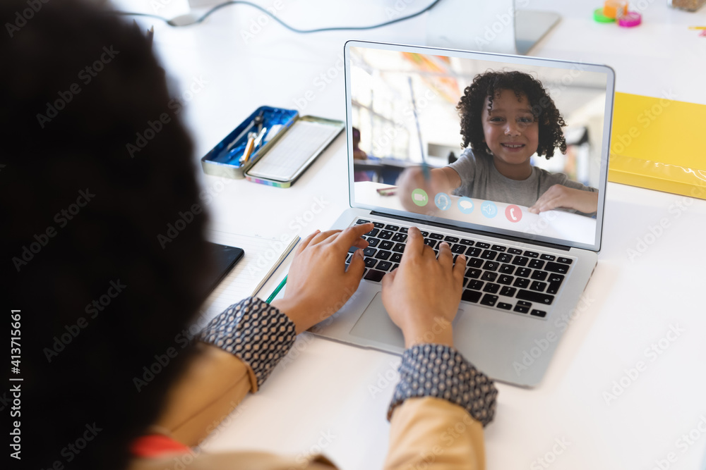 Mid section of female teacher having a video call with male student on laptop at school