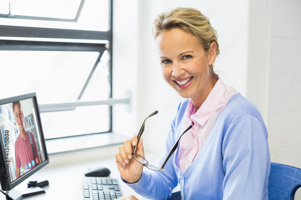 Portrait of female caucasian teacher having a video call with male student on computer at school