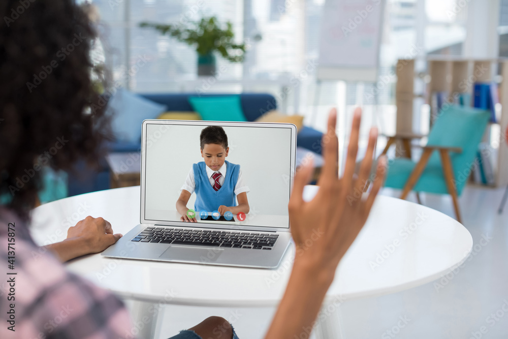 Female teacher having a videocall with male student on laptop at home