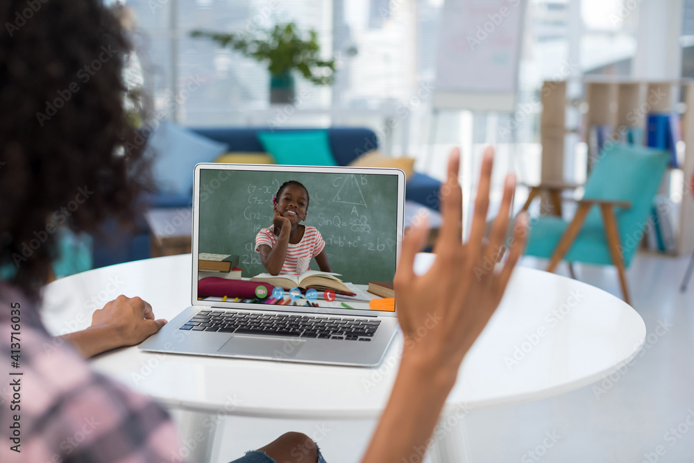 Female teacher having a video call with female student on laptop at school