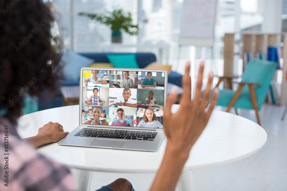 Female teacher having a video conference with multiple students on laptop at school