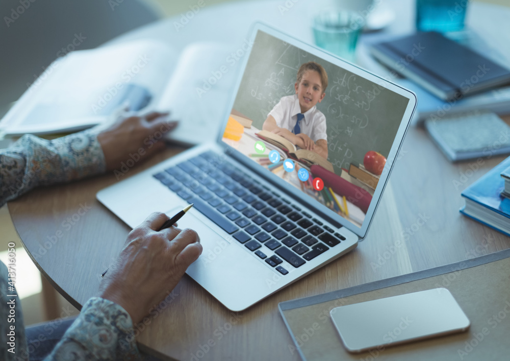 Mid section of female teacher having a video call with male student on laptop at school