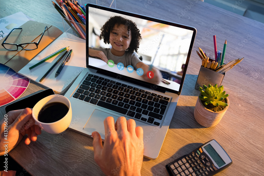 Mid section of teacher having a video call with male student on laptop at school