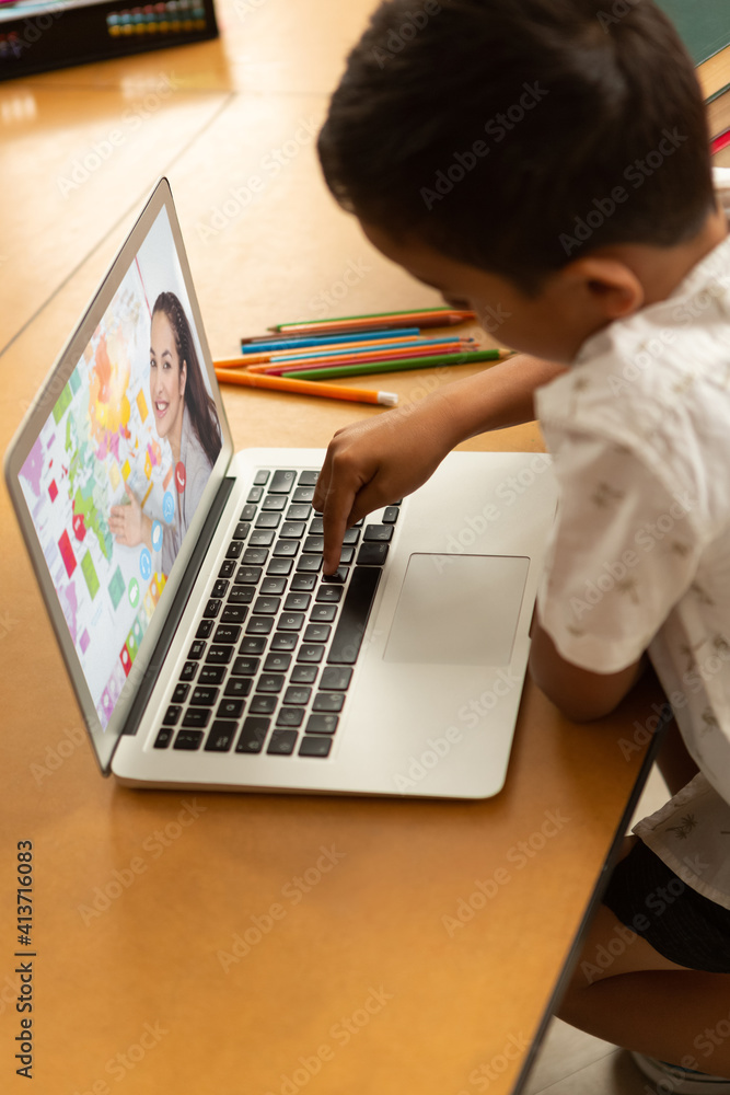 Male student having a video call with female teacher on laptop at school