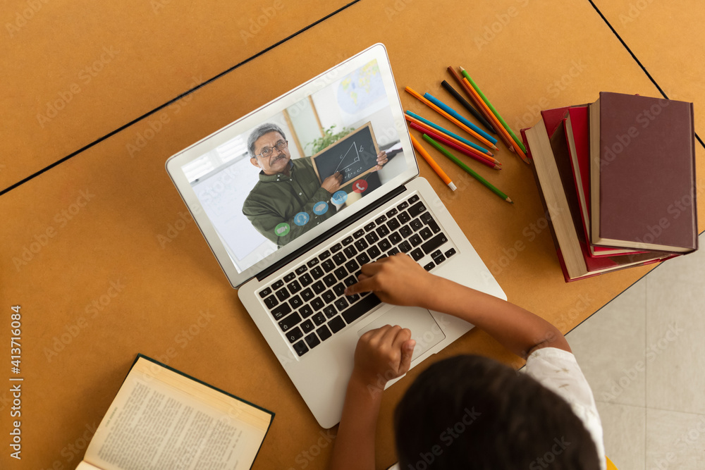 Overhead view of male student having a video call with male teacher on laptop at school