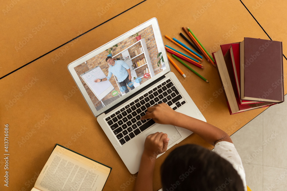 Overhead view of male student having a video call with male teacher on laptop at school