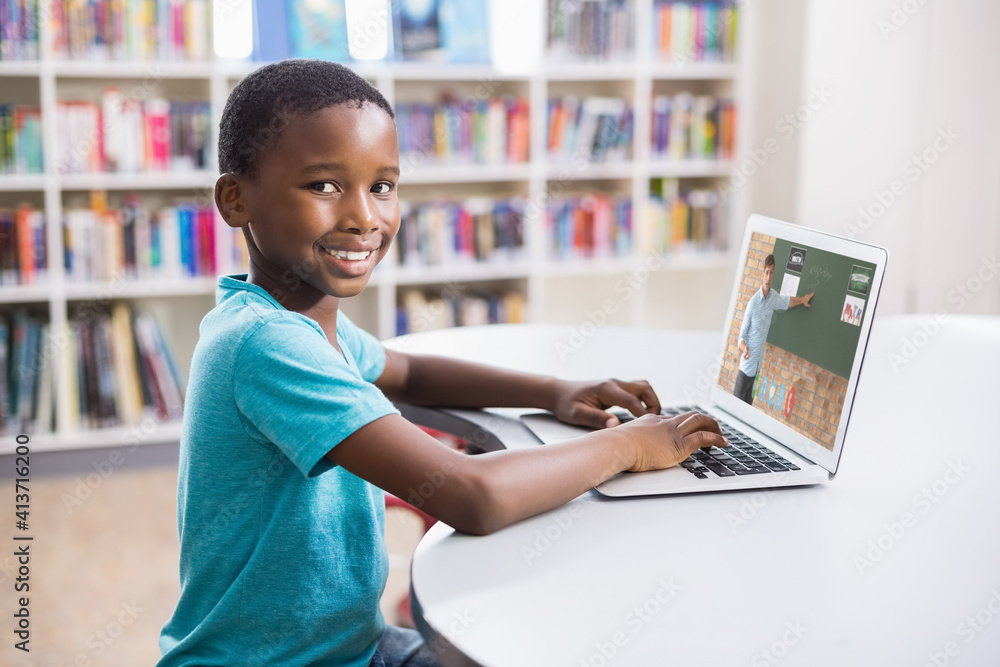 Portrait of male african american student having a video call with male teacher on laptop at library