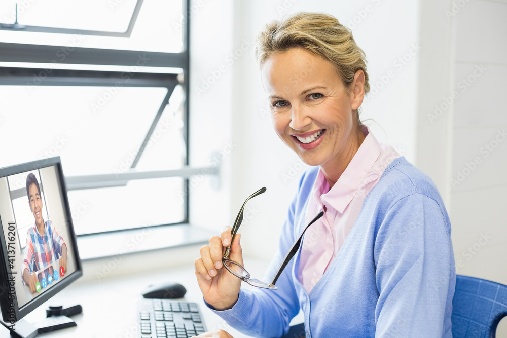 Portrait of female teacher having a video call with male student on computer at school