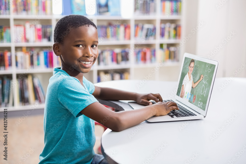 Portrait of male african american student having a video call with female teacher on laptop at libra