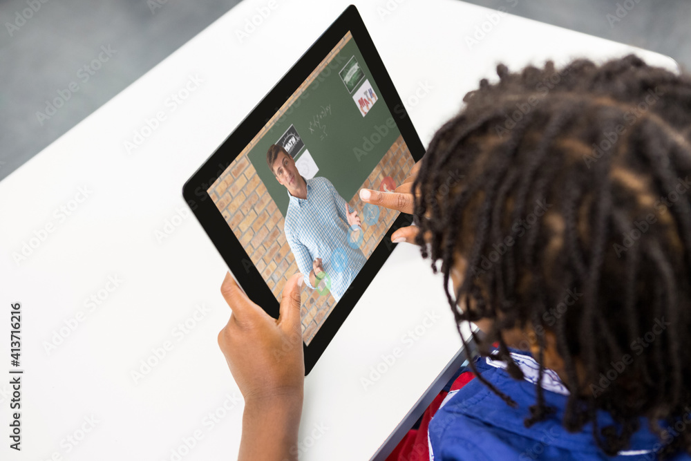 Male student having a video call with male teacher on digital tablet at school