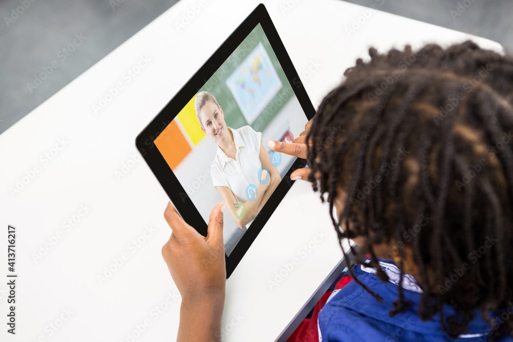 Male student having a video call with female teacher on digital tablet at school