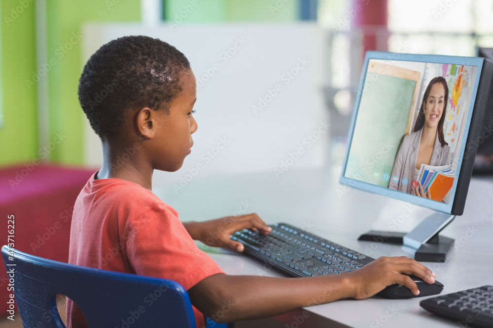 Male african american student having a video call with female teacher on computer at school