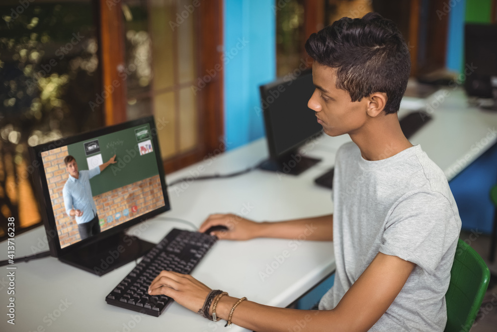 Male indian student having a video call with male teacher on computer at school