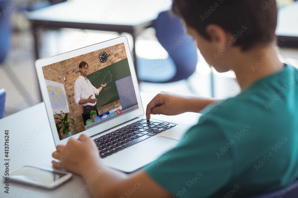 Male caucasian student having a video call with male teacher on laptop at school