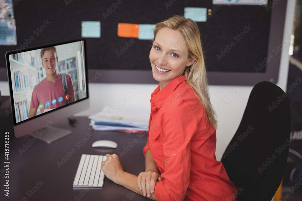 Portrait of female teacher having a video call with male student on computer at school