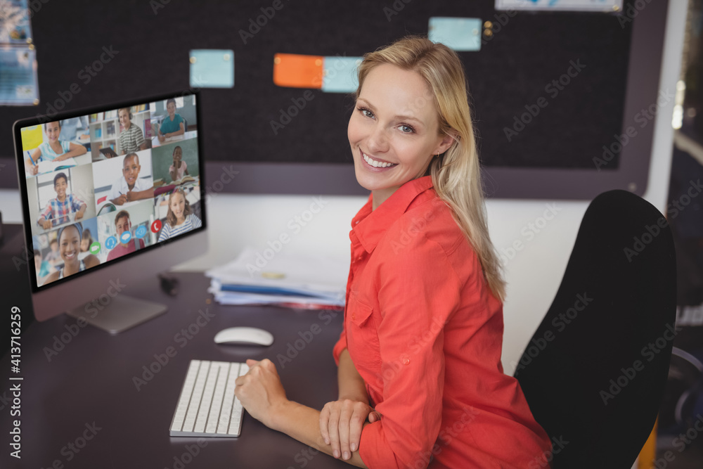 Portrait of female teacher having a video conference with multiple students on computer at school