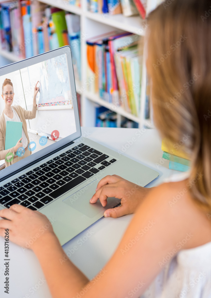 Female student having a video call with female teacher on laptop at the library