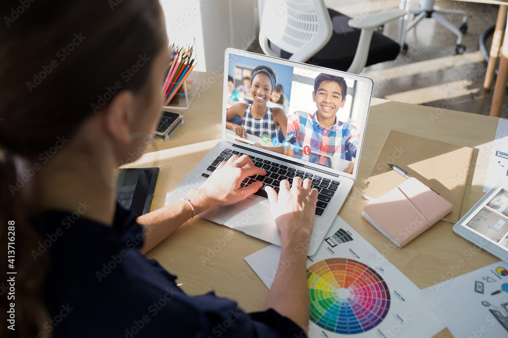 Female teacher having a video conference with male and female students on laptop at school