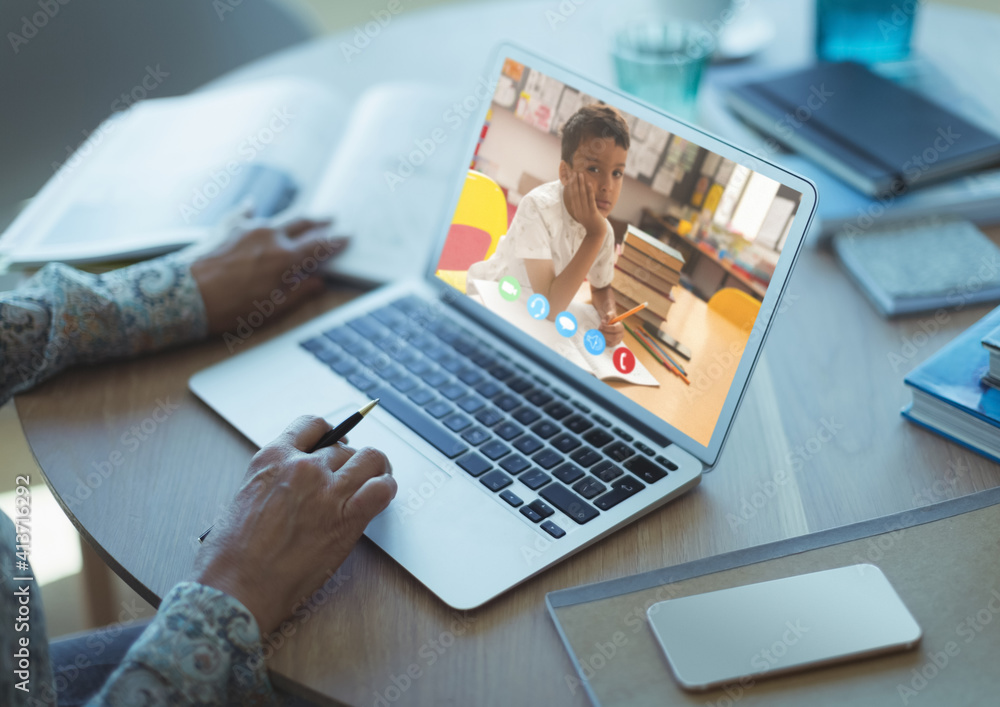 Mid section of female teacher having a video call with male student on laptop at school