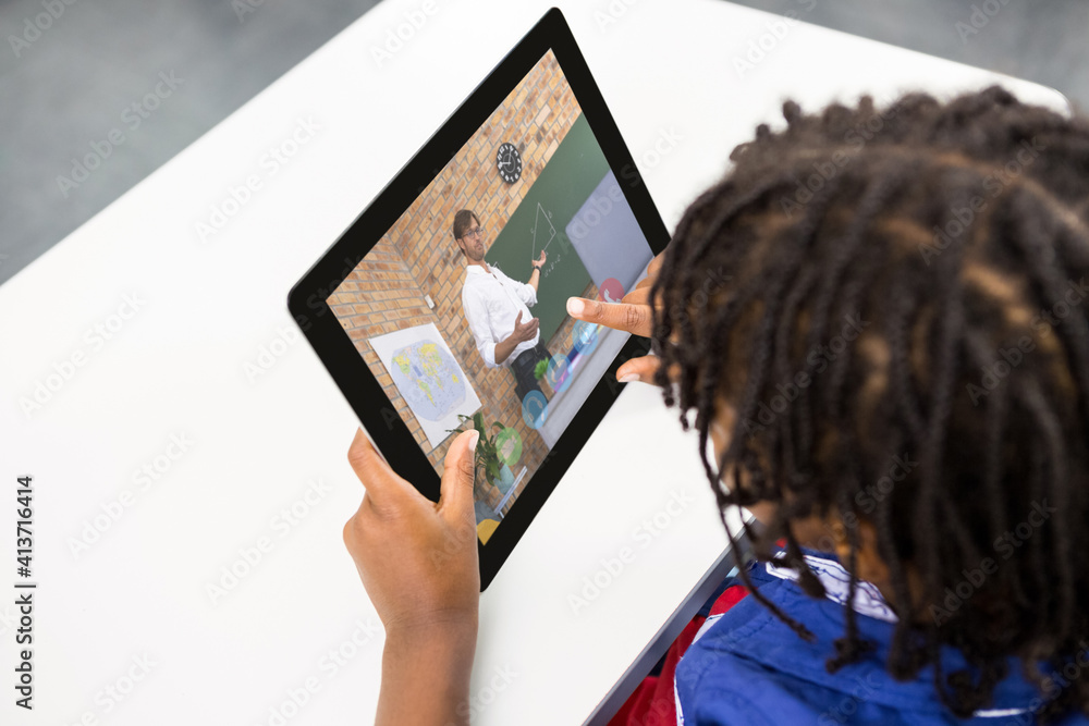 Male student having a video call with male teacher on digital tablet at school