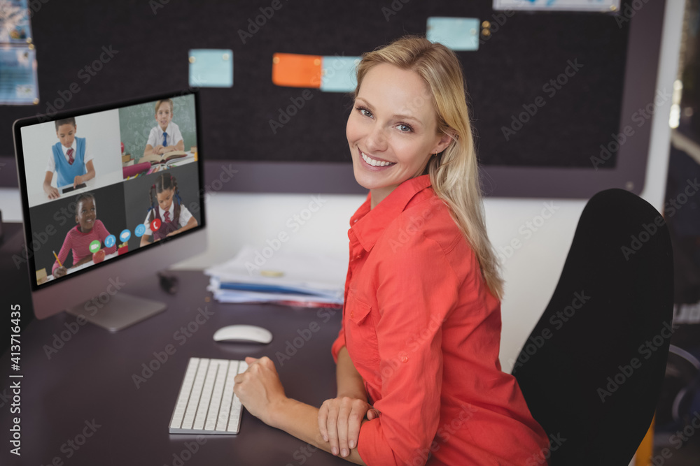 Portrait of female teacher having a video conference with multiple students on computer at school