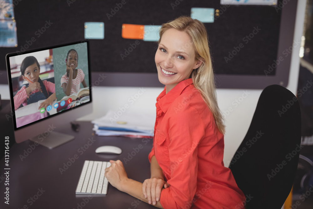 Portrait of female teacher having a video conference with two female students on computer at school