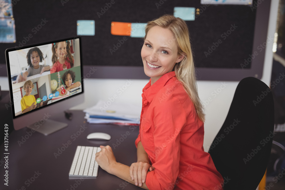 Portrait of female teacher having a video conference with multiple students on computer at school