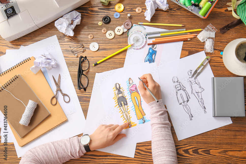 Female fashion designer working with sketches in studio, closeup